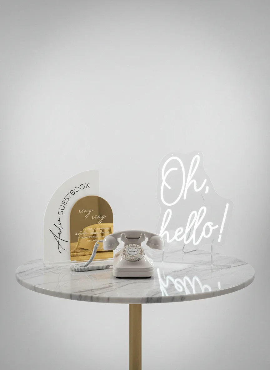 A vintage corded phone beside an 'Oh, hello!' neon sign on a marble table